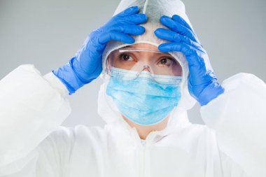 Beyaz koruyucu giysi, mavi cerrahi maske lateks eldiven ve güvenlik gözlükleri, Coronavirus COVID-19 pandemik kriz koruyucu kişisel ekipman eksikliğine yol açıyor.
