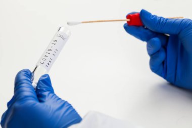 COVID-19 Coronavirus küresel salgını, eldiven ellerindeki çubuk test tüpü, PCR evdeki hasta örnek toplama kitinde, steril numune analiz için hazır, virüs hastalığının tespiti için hazır