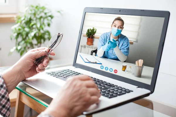 Virtual doctor visit,telemedicine healthcare concept,young female doctor giving advice over laptop computer screen to elderly woman,hands holding glasses & medical worker on display,remote appointment