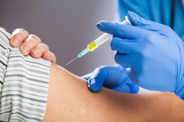 Coronavirus COVID-19 immülasyon konsepti, mavi koruyucu lateks eldivenli, sarı sıvıyla dolu bir şırınga taşıyan, hasta aşısına doz veren, Kafkas el kapatma detayı