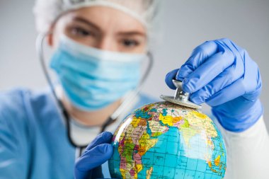 Dünya gezegenini dinlemek ve tanı koymak için stetoskop kullanan doktor, küresel sağlık kontrolü kavramı, COVID-19 virüsü hastalığı, Coronavirüs salgını, küresel salgın salgını