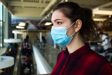 Korumacı bir yüz maskesi takan, alışveriş merkezinde ya da süpermarkette duran, Coronavirus COVID-19 'un gelecekten endişeli ve stresli güzel, oldukça endişeli genç bir kadın.
