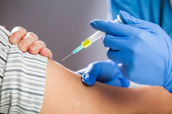 Coronavirus COVID-19 immülasyon konsepti, mavi koruyucu lateks eldivenli, sarı sıvıyla dolu bir şırınga taşıyan, hasta aşısına doz veren, Kafkas el kapatma detayı