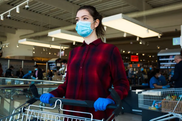 Business as usual,open again as normal,new norm for everyday activities after COVID-19 Coronavirus pandemic end,obligatory personal protective equipment,face mask,gloves.Female shopper pushing trolley