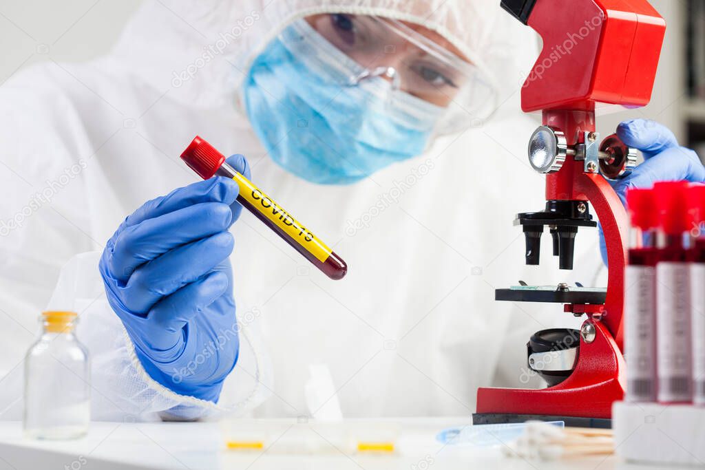 Medical technologist holding a COVID-19 test tube blood sample, contagious dangerous Coronavirus disease global pandemic outbreak, hazard patient specimen laboratory testing analysis procedure
