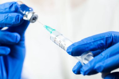COVID-19 aşı konsepti, küçük şişe ampulünden enjeksiyon iğnesi yapılan şırınga, Coronavirus aşılama dozunu hazırlayan İngiliz laboratuvar teknisyeni veya hemşire, hasta tedavisi