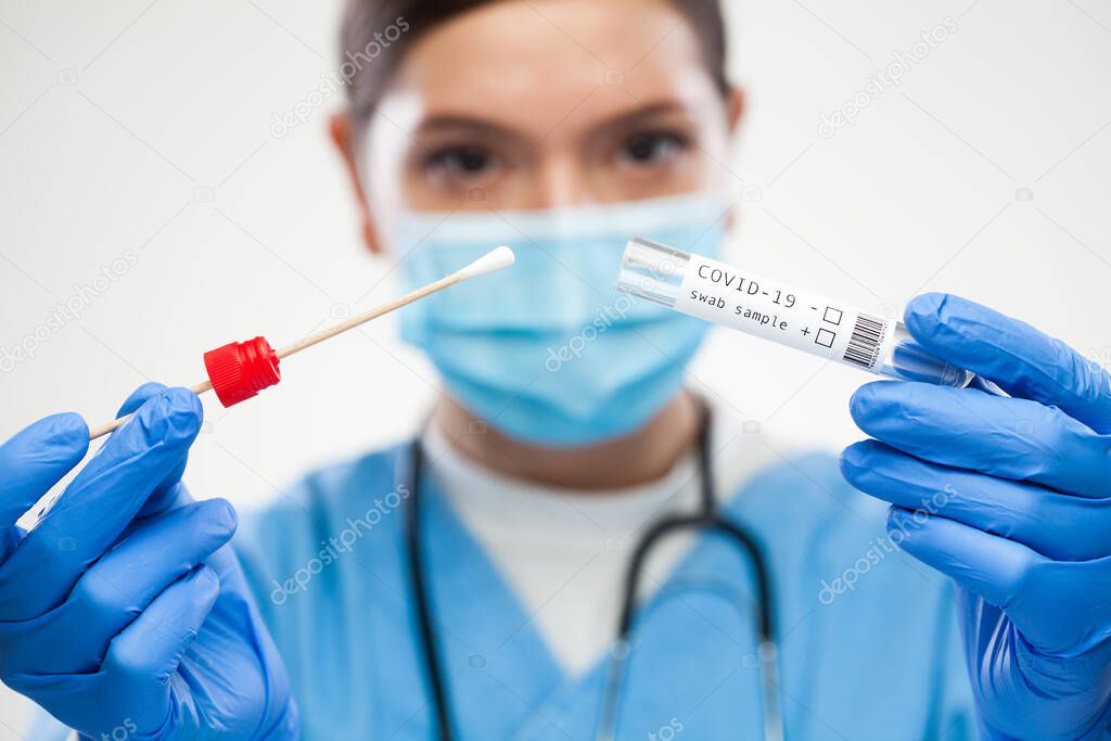 Female UK GP physician wearing personal protective equipment performing Coronavirus COVID-19 rt-PCR test,patient nasal NP oral OP swab sample specimen collection process,viral DNA diagnostic procedure