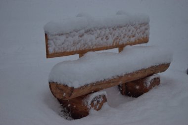 Taze kar, Lihtenştayn 'da Vaduz' da 14.1.2021 'de bir kar yağışı sırasında ahşap bir bankta yatar.