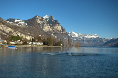 İsviçre, Weesen 'deki Walensee' de 21.2.2021 'de su fıskiyesi ve alp manzarası.