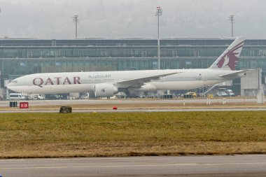 Zürih, İsviçre, 23 Ocak 2026 A7-BEV Katar Boeing 777-3DZER uçağı çok sisli bir günde kapıya doğru ilerliyor.