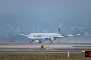 Zürih, İsviçre, 23 Ocak 2026 A7-BEV Katar Havayolları Boeing 777-3DZER uçağı çok sisli bir günde 28 numaralı pistten kalkıyor.