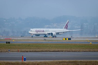 Zürih, İsviçre, 23 Ocak 2026 A7-BEV Katar Havayolları Boeing 777-3DZER uçağı çok sisli bir günde 28 numaralı pistten kalkıyor.