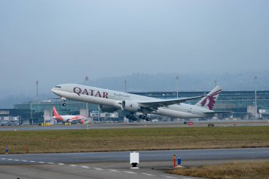 Zürih, İsviçre, 23 Ocak 2026 A7-BEV Katar Havayolları Boeing 777-3DZER uçağı çok sisli bir günde 28 numaralı pistten kalkıyor.