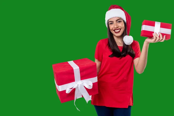 クリスマスの帽子をかぶった女性は緑の背景に隔離された贈り物を持っています — ストック写真