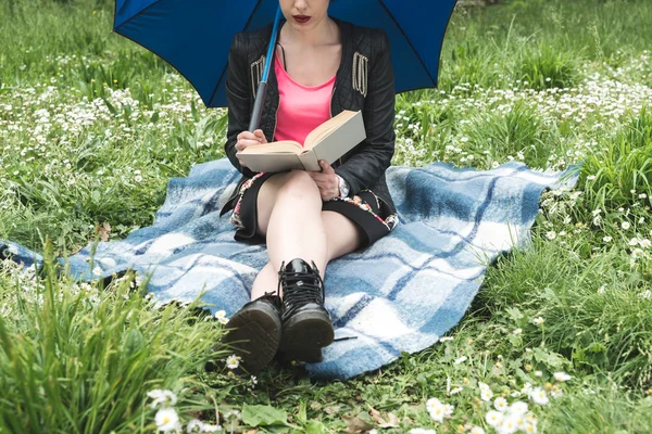 Girl under the rain reading a book in a garden Stockfoto