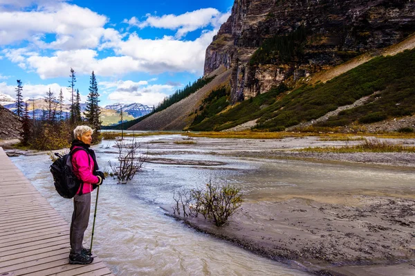 Starší žena pozorování voda z ledovce Lefroy odvodňovaná do Lake Louise a Victoria — Stock fotografie