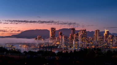 Güneş Vancouver, British Columbia, Kanada 'nın Skyline üzerinde batarken, sis Granville Köprüsü üzerinde sürükleniyor. Falls Creek 'in güney kıyısından bakıldığında