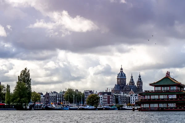 Katedralen och hus från medeltiden med kinesiska flytande byggnad i Amsterdam — Stockfoto