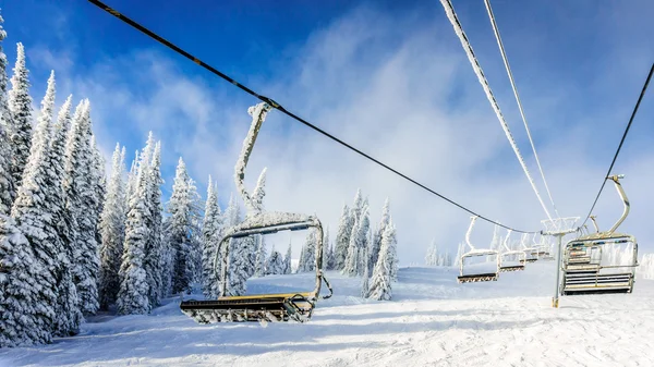 Empty, snow and ice covered ski lift chairs on a cold winter day