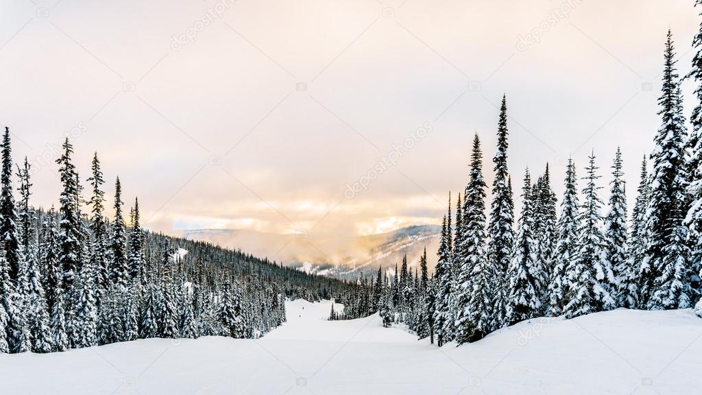 Sun breaking through the clouds on a ski hill in central British Columbia