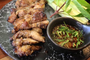 Lezzetli dilimlenmiş domuz bifteği. Bitki ve baharatlı sosla süslenmiş. Gurme restoranındaki siyah taş tabakta servis ediliyor.