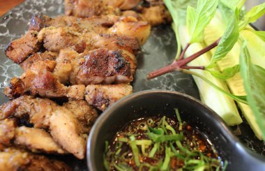 Lezzetli dilimlenmiş domuz bifteği. Bitki ve baharatlı sosla süslenmiş. Gurme restoranındaki siyah taş tabakta servis ediliyor.