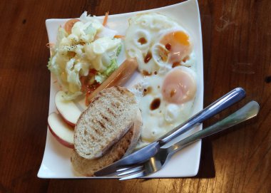 Ev yapımı kahvaltı, taze yumurta, sosis, salata ve tost, beyaz tabakta servis edilen ahşap masa, İngiliz yemekleri, amerikan yemekleri Frhstck, yemek arkaplan reklamları.