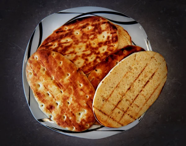 Gaz ızgarasında kızartılmış ekmek. Tortillalar tabakta yatıyor..
