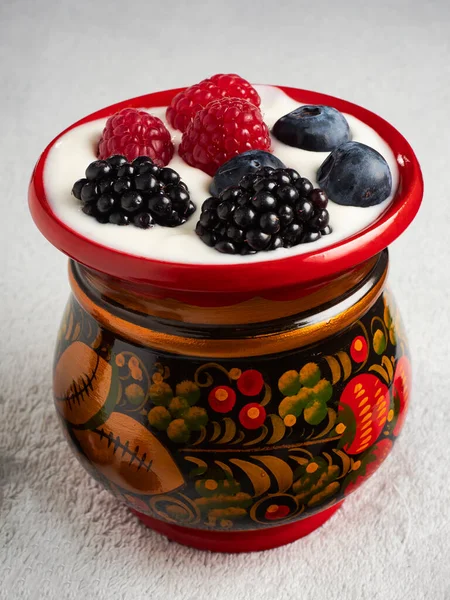 Wooden red patterned cup with berries and yogurt inside.Healthy eating