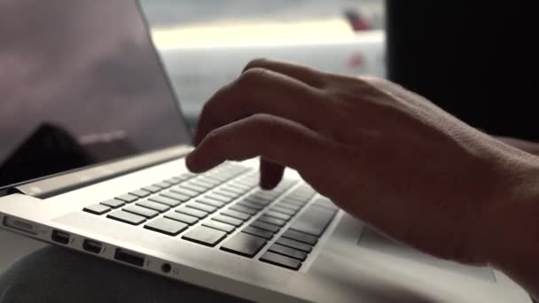 Een mens schrijft iets op de laptop in de vertrekhal van de luchthaven — Stockvideo