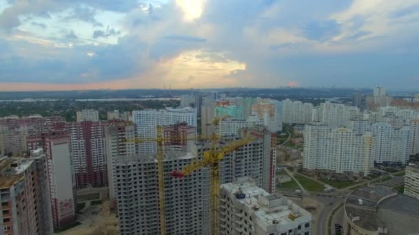 Aérea. Sitio de construcción con muchas grúas en una gran ciudad. Tiempo de puesta del sol — Vídeos de Stock