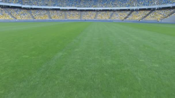 Volando por encima de la hierba en una pequeña altura dentro de un enorme estadio vacío moderno — Vídeos de Stock