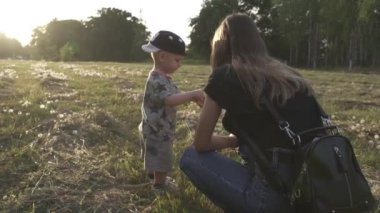 Yavaş çekim. Anne ve küçük çocuk çayırda oynuyorlar.
