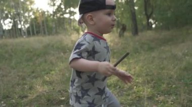 Yavaş çekimde. Çayırda oynayan küçük çocuk.