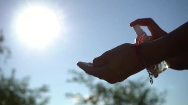 Güneşli bir günde kadın elinin antiseptik kullandığını gösteren yavaş görüntüler.