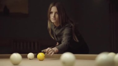 Bilardo oynayan kız. Oyuncu atış için bir top belirledi