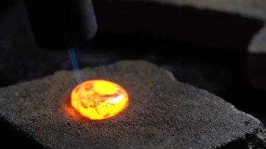 Gümüş damlası mücevher atölyesinde gaz ocağıyla eritilmiş. Kapat.