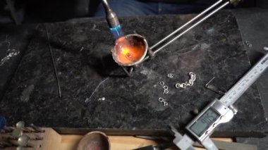 Mücevher, küçük mücevher tabağında yanan gümüşü eritiyor.