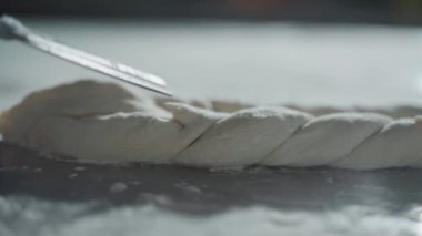 Şefin hamuru pişirmek için hazırlarken çekilmiş yakın çekim görüntüleri, hamuru makasla kesen adam ham hamur üzerinde bazı şablonlar.