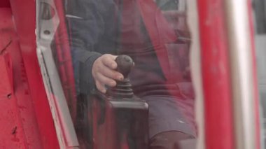 Bir adam, karlı bir inşaat alanını gözleyen kırmızı ağır makineler kullanıyor.