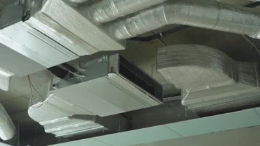 Birçok endüstriyel metal hava kanalları ve havalandırma boruları modern tesisin beton tavanına monte edilmiştir..