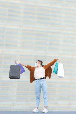 Coronavirus salgını sırasında alışveriş. Alışveriş torbalarını tutan mutlu ve gururlu bir genç kadın..