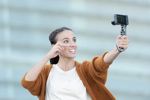 Social media content creation concept. A young woman recording a tutorial and holding a compact camera