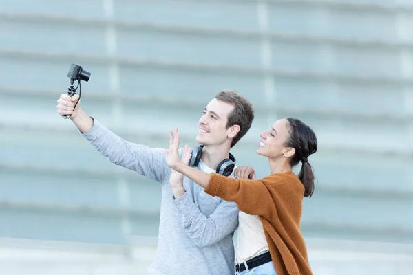 Social media content creation concept. A young couple greeting to the camera while recording themselves.