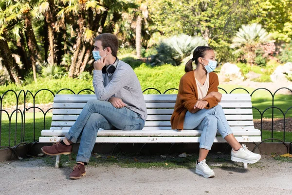 在结肠病毒大流行期间的社会疏离 一位男女青年坐在公园的长椅上 向两边张望 以避免传染 — 图库照片