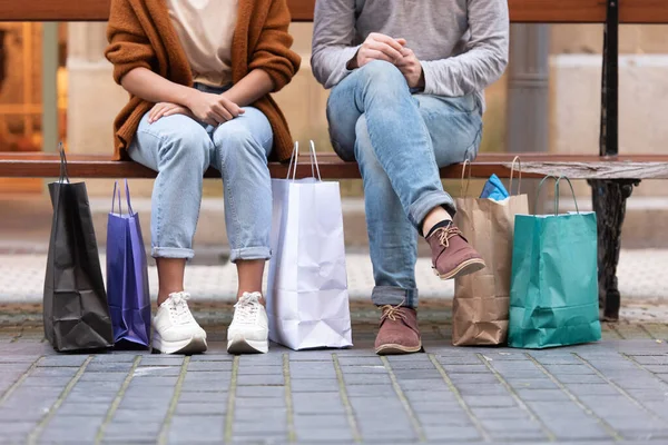 Alışveriş torbalarıyla bankta oturan bir çift..