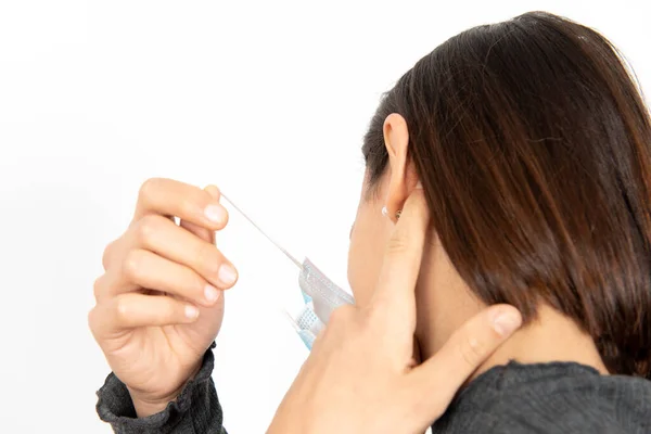Tıbbi maskenin kulak ilmiği yüzünden kulakları ağrıyan bir kadının arka plan görüntüsü. Coronavirüs salgını sırasında sağlık hizmetleri.