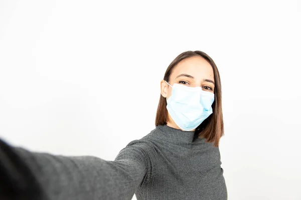 Tıbbi maske takan ve selfie çeken Latin bir kadının yakın plan portresi. Coronavirüs salgını sırasında sağlık hizmetleri.