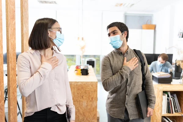İspanyol iş arkadaşları ellerini göğsüne koyup selamlıyorlar. Coronavirus salgını sırasında ofiste çalışmak.