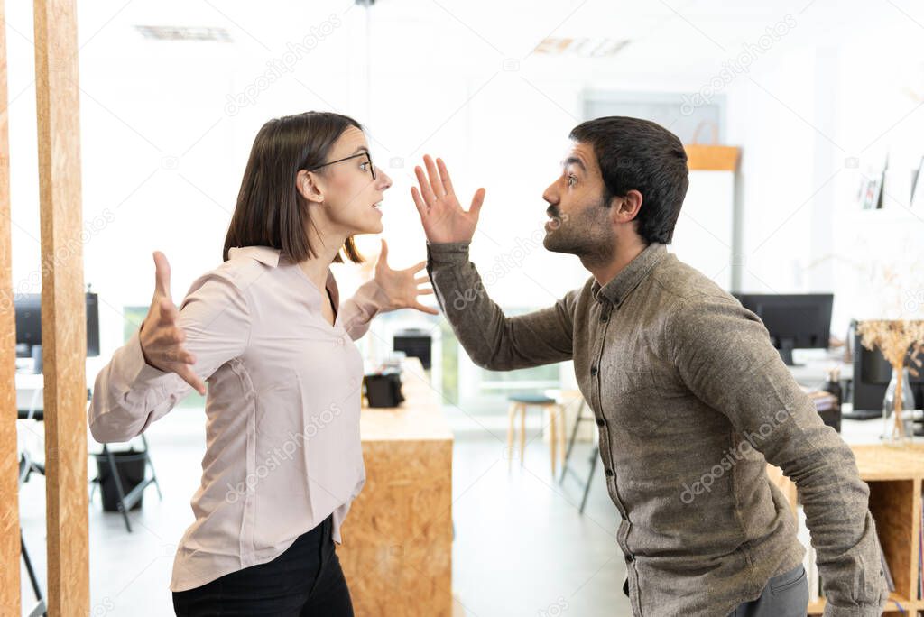Angry hispanic coworkers discussing and arguing at the office.